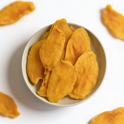 Dried mango slices in a small white bowl on a light background