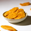 Dried mango pieces in a white bowl on a light background